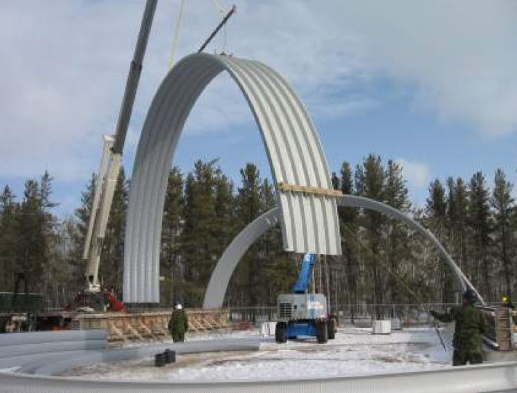 Sheet metal formed and seamed into 5’ sections are lifted into position onto a concrete pony wall.