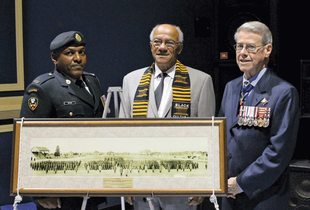 A photo of the No. 2 Construction Battalion on parade grounds in 1916 ipresented to Lt. Gov. Jim Grant, by Dr. Les Oliver, president of the Black Cultural Society. With them is Chief Warrant Officer Steven Milton.