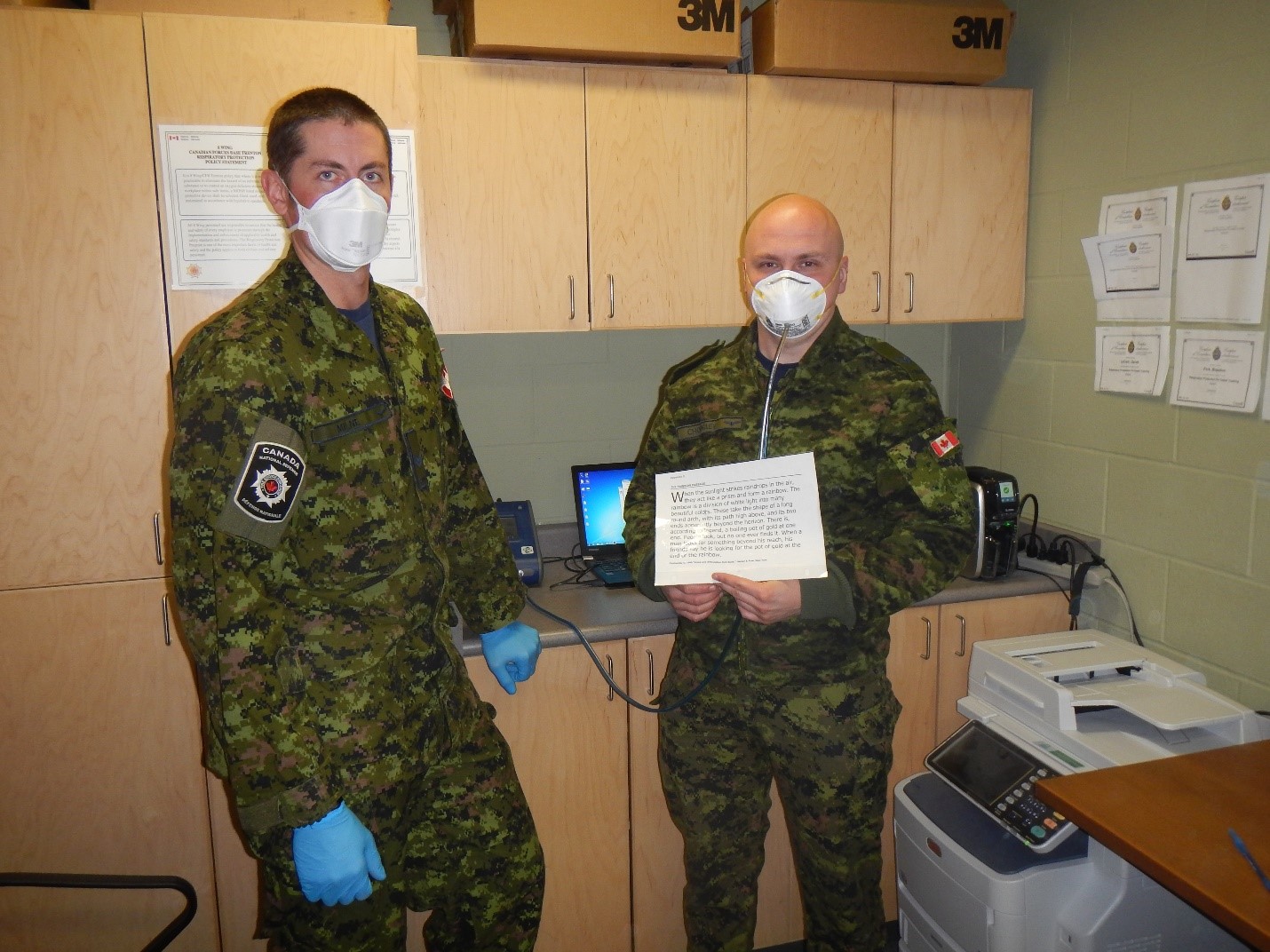 Cpl Milne (left) administers an N95 mask fit test to a member of 8 Wing Trenton. 