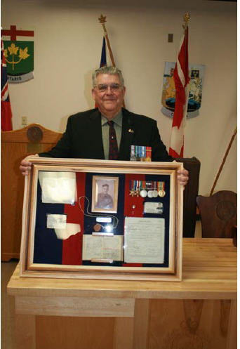Le Maj Fred Gallant pose avec les documents de service et les médailles de son père. Photo prise par le Cplc Merner, EGMFC