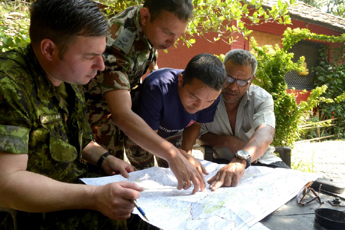 Capt James Borer, a CIMIC officer attached to DART Capt Animesh Adhikari, Nepalese National Army LO, discuss roads status with local authorities. // Le capt James Borer, un officier de CIMIC avec l’EICC le capt Animesh Adhikari, un officier de liaison pour l’armée nationale népalaise, discutent de la condition des routes.
