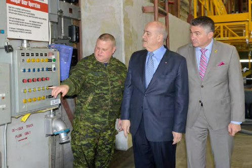 Julian Fantino and James Bezan learn how to operate hangar doors with Sgt Mike Purll, from 402 Sqn at 17 Wing Winnipeg. // Julian Fantino et James Bezan apprennent comment faire fonctionner les portes de hangar avec le Sgt Mike Purll, du 402e Escadron à la 17e Escadre Winnipeg.