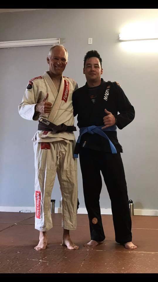 Chad Gibbons (R) receiving his blue belt from Professor Chris Kading (L) at the Winnipeg Academy of MMA in Brandon in 2018.