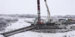 Battling winter conditions, contractors prepare for the installation of the first circular pile that secures the bridge // Luttant contre les conditions hivernales, les entrepreneurs se préparent à installer le premier pieu circulaire qui sécurisera le pont