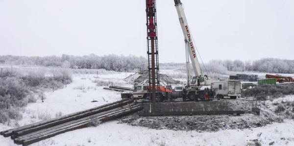Battling winter conditions, contractors prepare for the installation of the first circular pile that secures the bridge // Luttant contre les conditions hivernales, les entrepreneurs se préparent à installer le premier pieu circulaire qui sécurisera le pont